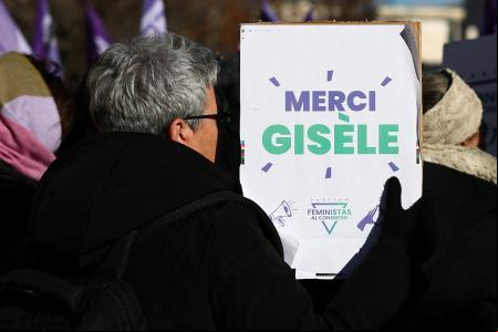 A woman holds a placard which reads