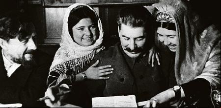 Soviet leader Joseph Stalin autographs photographs for 11-year-old Mamlakat Nakhangova (left of Stalin) and Ene Geldiyeva (right),  of a farming collective from Tajikistan who went to Moscow to confer with Stalin. M.A. Chernov, the people's commissar for agriculture, is at the far left. (Photo by © Hulton-Deutsch Collection/CORBIS/Corbis via Getty Images)