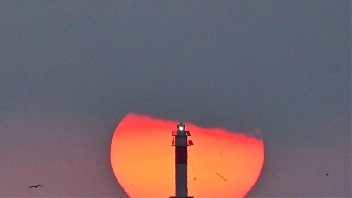 El amanecer del sol recortado del faro del Fangar